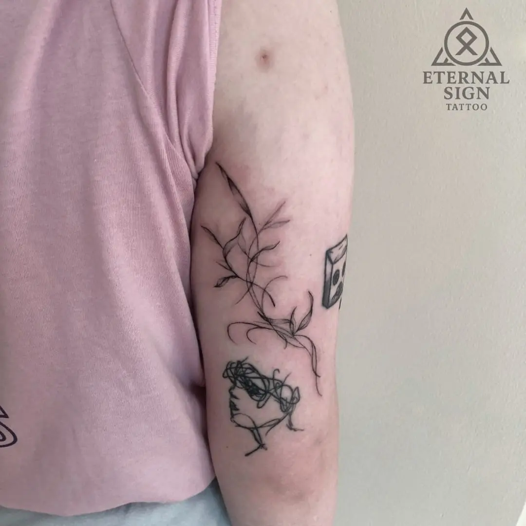 Linework tatovering av blomster og liten fugl på overarmen i Fredrikstad